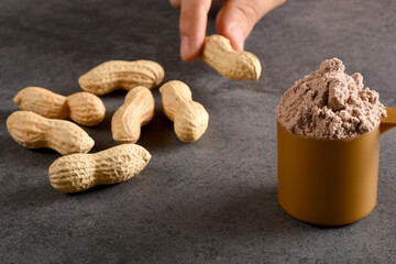 Choosing natural protein or protein powder, a male hand choosing peanuts instead of protein powder