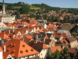 Fototapeta premium An aerial view of Cesky Krumlov’s old town, including several siena-coloured rooftops and a church tower on a sunny day with a blue sky. Image has copy space.