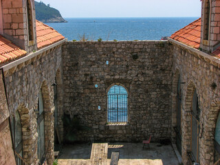 A part of Dubrovnik's city wall including a barred window overlooking the Adriatic Sea on a sunny day with a clear blue sky.  Image has copy space.