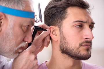 Young male patient visiting old male doctor otologist
