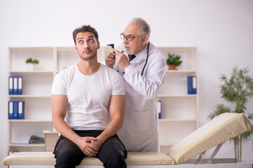 Obraz premium Young male doctor visiting old doctor otolaryngologist