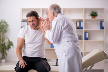 Obraz premium Young male doctor visiting old doctor otolaryngologist