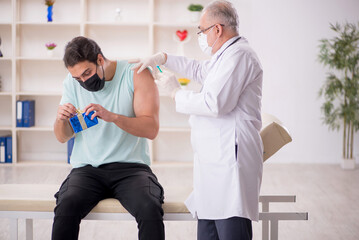 Fototapeta premium Old male doctor giving giftbox to young male patient