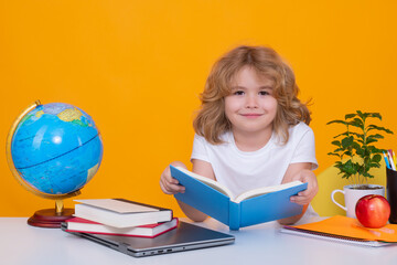 School child reading book. Back to school. Funny little boy from elementary school with book. Portrait of school boy isolated on yellow studio background. Education.