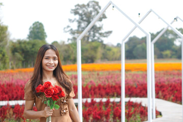 Asian woman smiling happily among beautiful flowers