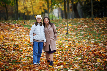 Naklejka premium Mom and daughter in the autumn park. Woman and teen girl outdoors.