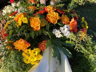 Trauerkranz mit Blumen in gelb und orange auf dem Friedhof nach Beerdigung