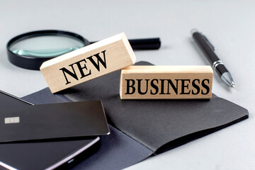 NEW BUSINESS text on wooden block on black notebook , business concept