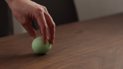 Young man spin easter egg on walnut table