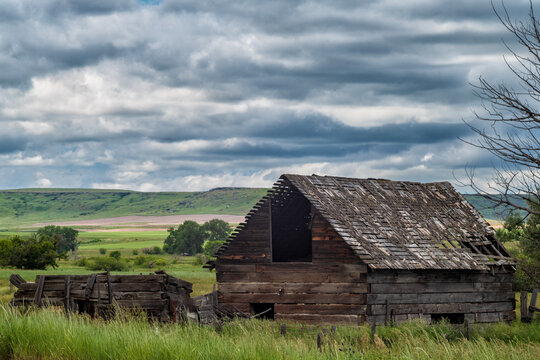 An abandoned wood farm house stands in the grasslands of Pryor, Montana a during stormy afternoon.