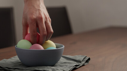 Man hand put easter egg in a bowl on walnut table