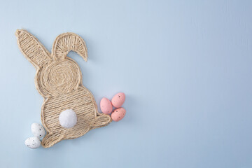 Handmade easter bunny made of strings with eggs on a light background, top view