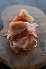 Thin slices of jamon on olive wood board