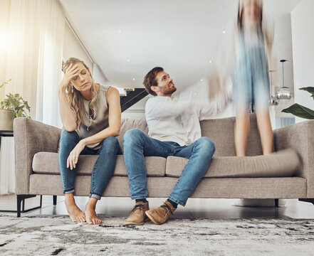 Family life stress, parents and child, chaos at home and energy, motion blur and burnout headache. Kid jump on couch, woman has migraine and man calming girl, hyperactive with ADHD and mental health