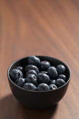 Blueberries in black ceramic bowl on walnut table