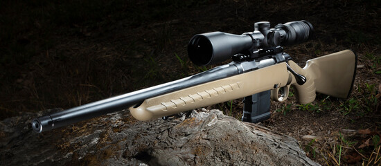 Beige 556 botl action rifle with a scope in the woods