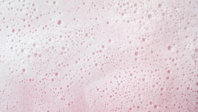 Water wave flows creating a lot of foam on pink background | Background shot for skin hydrating cosmetics commercial