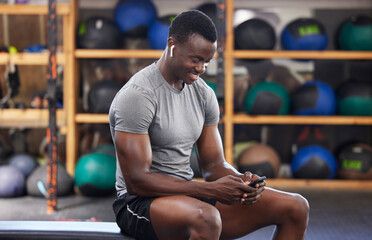 Fototapeta na wymiar Phone, fitness and black man in gym training, workout or exercise social media or internet search for health tips. Bodybuilder, sports person listening to music or typing on smartphone chat or mobile