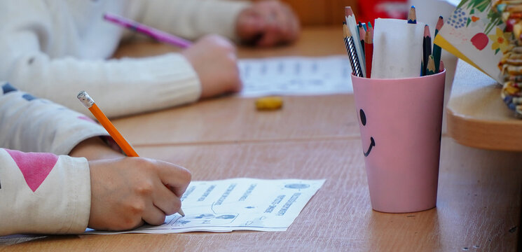 Cute student writing at the desk in the elementary school classroom. A student taking the test in primary school. Children writing notes in class. schoolgirl writing during lesson.