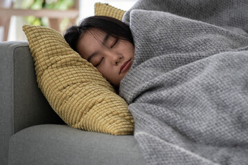 Calm tired Chinese Asian girl resting relaxing sleeping on sofa in living room after work relieving negative emotions. Exhausted Korean young female taking nap daydream after education. Stress free.