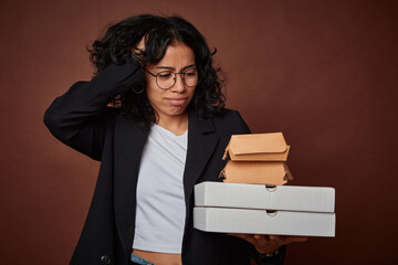 Young business woman holding a fast food pack being shocked, she has remembered important meeting.