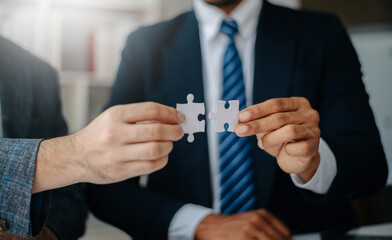 Business solutions and success concept. Businessman hand connecting jigsaw puzzle at office in morning light..