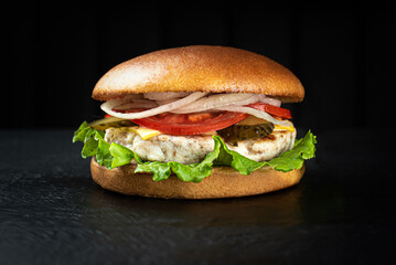 Cheeseburger on a black wooden background looks appetizing