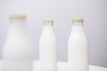 Drei Glasflaschen mit Milch vor weißen Hintergrund