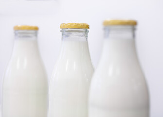Drei Glasflaschen mit Milch vor weißen Hintergrund
