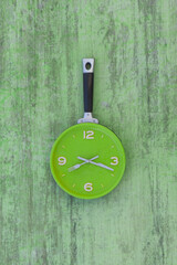 kitchen wall clock on green wooden background