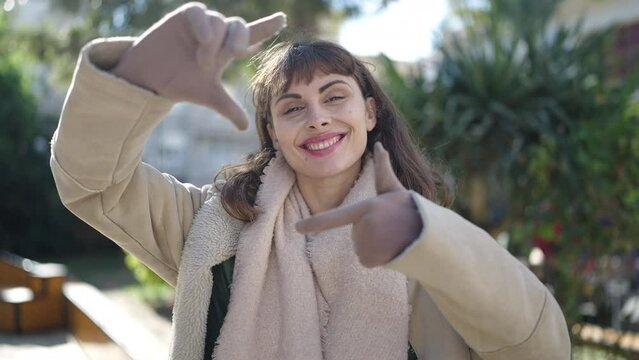 Young caucasian woman smiling confident doing photo gesture with hands at park