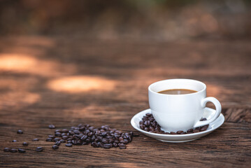 black drip coffee in ceramic cup on old wood table with coffee bean. Barista serve cup of hot black coffee on old wooden table cafe shop in garden with coffee bean.