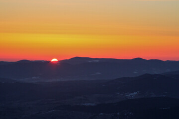 Obraz premium Orange sky at sunrise in dark winter mountains