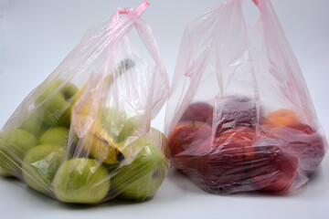 Two large packets of fruit, healthy food, many red, ripe apples and green apples with a ripe banana lie in pink disposable bags.