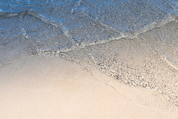 Ocean wave on tropical beach with golden sand and ripple of water splash from emerald blue-green sea water during summer vacation. 