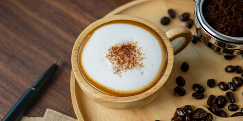 Hot coffee espresso latte with milk froth foam in wood cup. barista pouring milk liquid froth foam to wood cup of espresso for make creamy cappuccino hot drink.