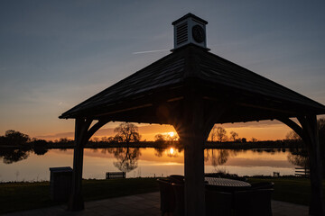 Silhouette of a gazebo next to a lake at sunset in winter