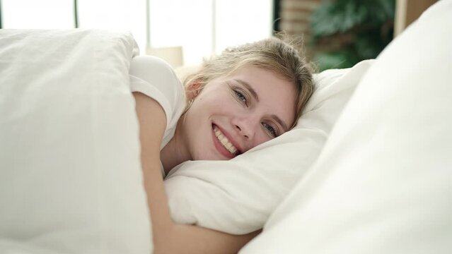 Young blonde woman smiling confident lying on bed at bedroom