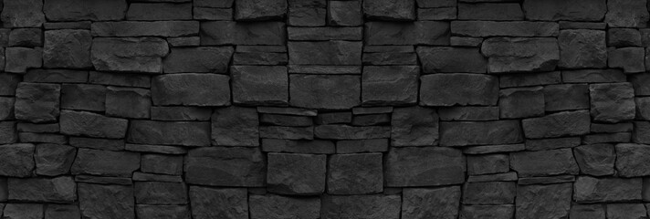 Black stone wall wide texture. Rough rock masonry wallpaper. Dark gloomy grunge background
