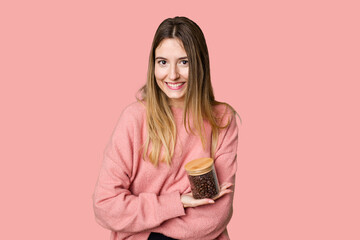 Young woman holding a container of coffee beans, symbolizing the energy and invigoration of this beloved beverage laughing and having fun.