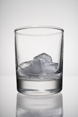 Close-up low cocktail glass with ice on the bar table with reflection