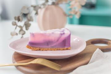 Piece of pink marble cake on a plate with forks and napkin. Bright colour background, close-up. 