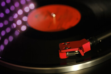 close-up of pickup head on vinyl record, color illumination, analogue retro music concept, hobby of collecting vinyl music discs, audio experience, relaxation, musical enjoyment, vintage technology © kittyfly