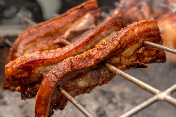 Several pieces of Liempo, or pork belly skewered on a spit and roasted on an oven at a roadside...