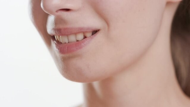 Extreme close-up shot of good-looking white-skinned woman with long brown hair strokes her jawline and chin smiling widely on white background | Flawless chin concept