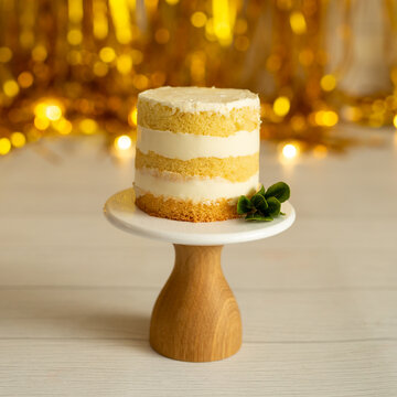 Celebration - a small cake on a stand against a background of golden decor