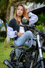 Fototapeta na wymiar Beautiful brunette woman sitting on a motorcycle, wears stylish denim clothes