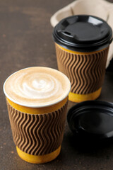 Paper cups with cappuccino on a stand on a brown table. coffee to go