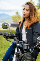 Fototapeta na wymiar Portrait biker woman in a denim clothes sits on a black motorbike