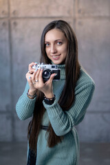 beautiful girl with an old camera in her hands in a green dress. looking at the camera smiling